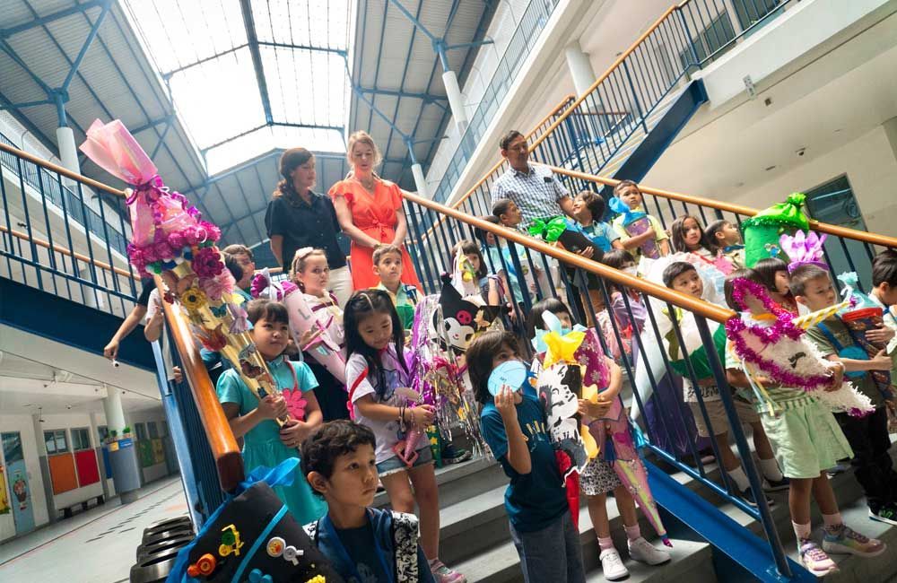 A group of children are standing on a set of stairs holding balloons.