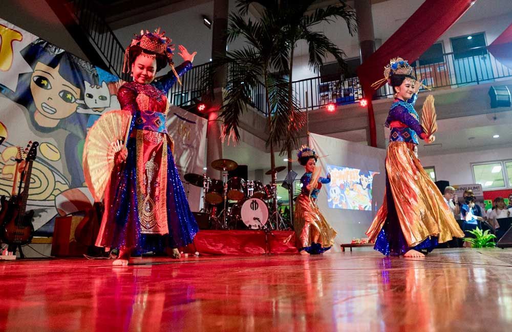 A group of women are dancing on a stage in a room.