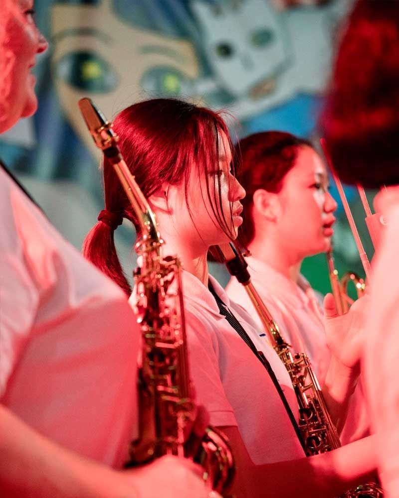 A woman is playing a saxophone in a band.
