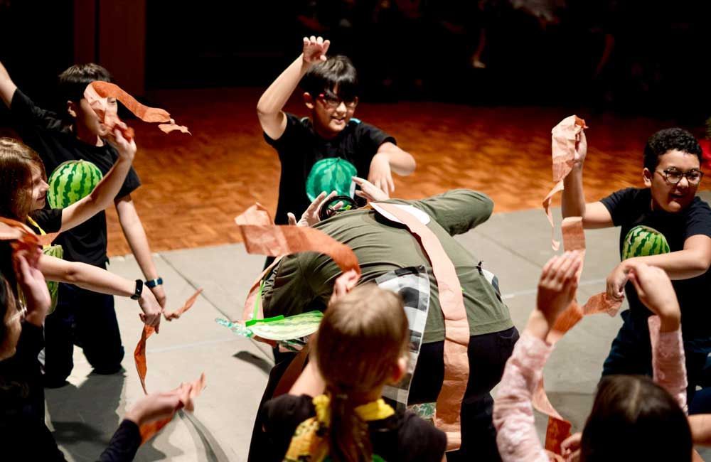 A group of children are playing with watermelons on a stage.