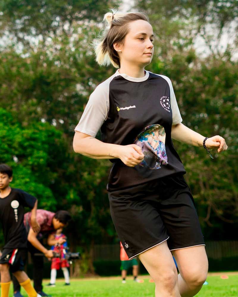 A woman in a black shirt and shorts is running on a field.