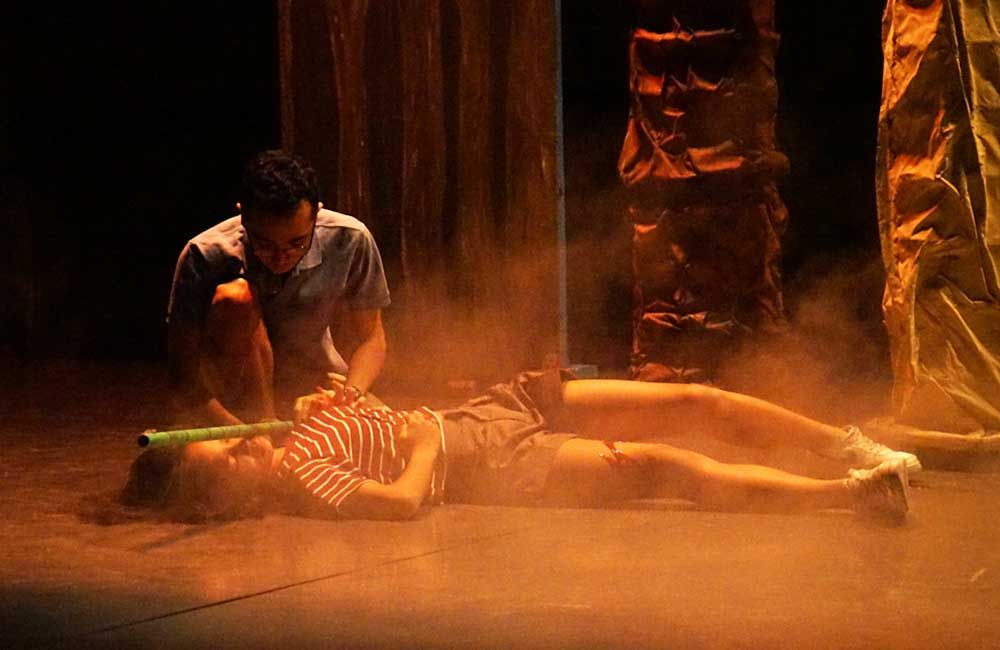 A man is kneeling next to a woman laying on the floor.