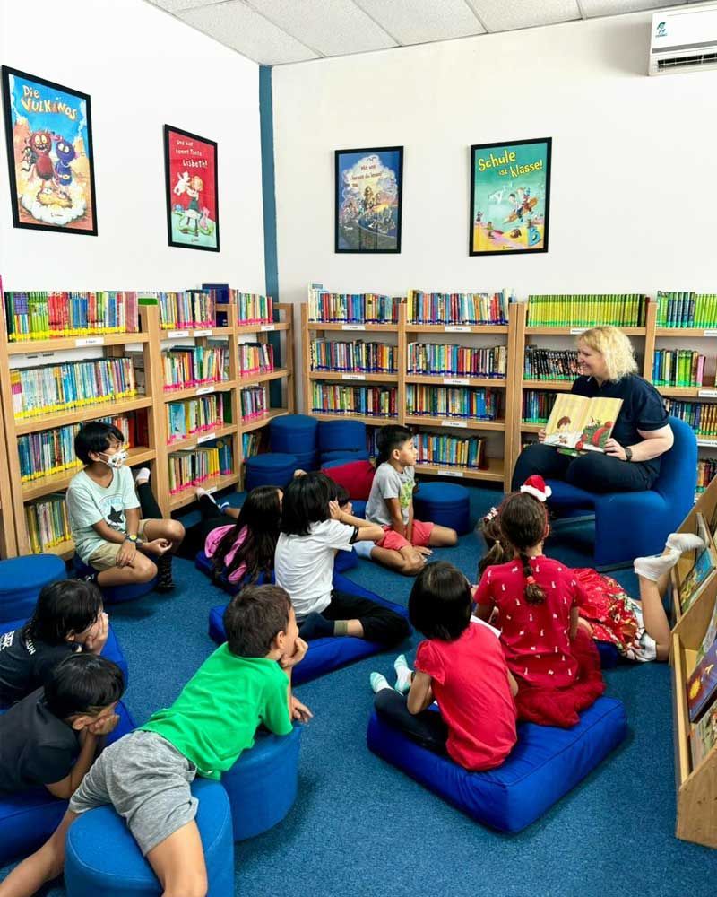 A woman is reading a book to a group of children in a library.