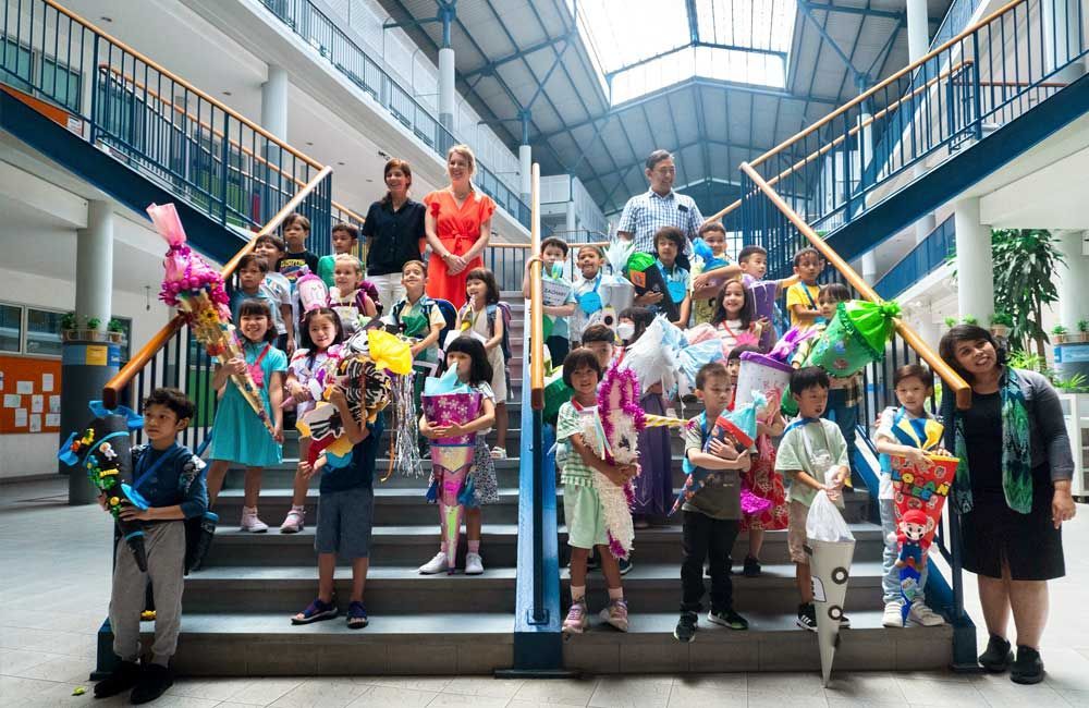 A group of children are posing for a picture on the stairs of a school.