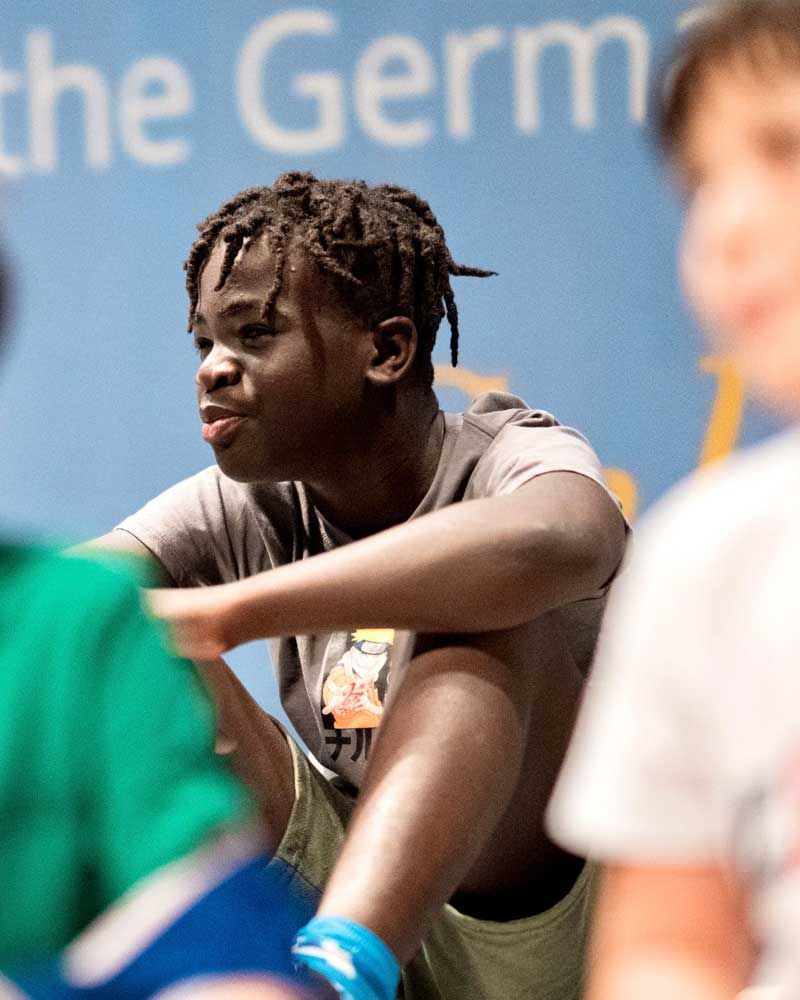 A boy sits in front of a sign that says the germ