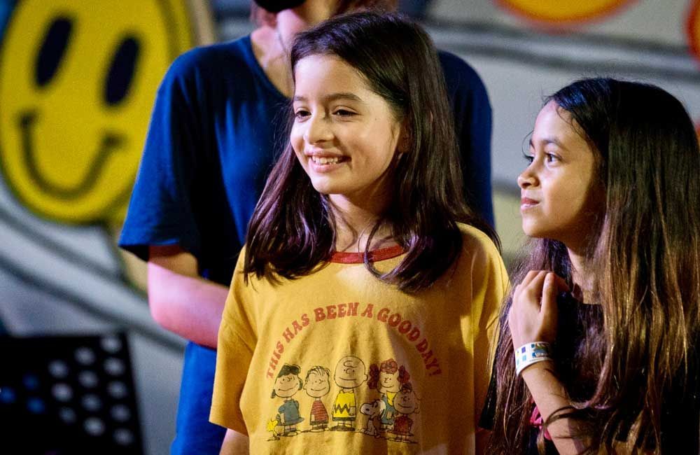 A group of young girls are standing next to each other in front of a smiley face.
