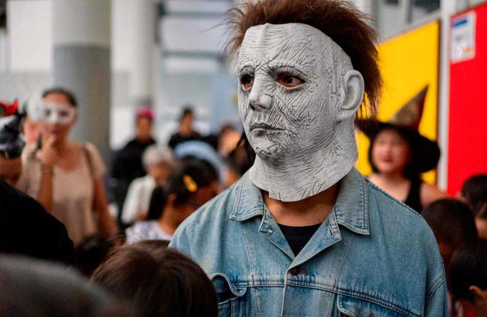 A man wearing a mask is standing in a crowd of people.