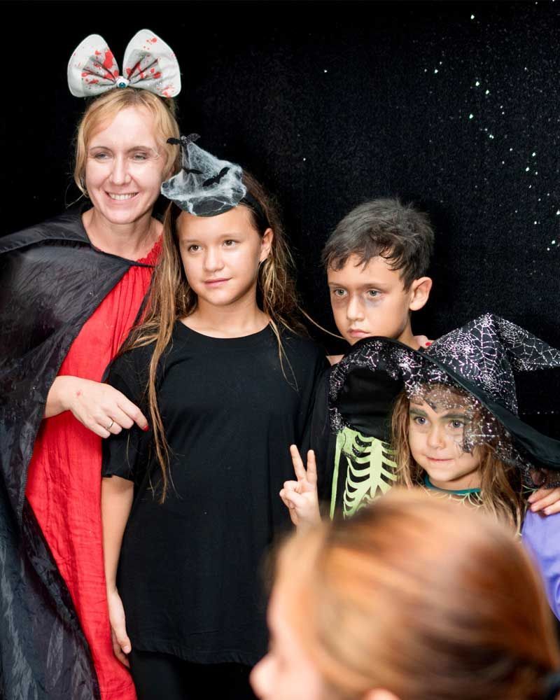 A woman is taking a picture of a group of children dressed in halloween costumes.