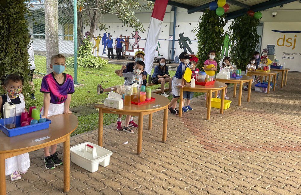 A group of children are sitting at tables wearing face masks.
