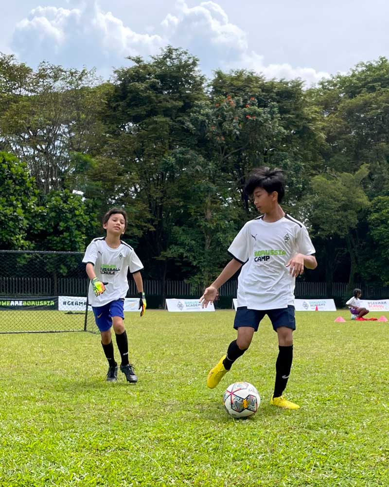 Two young boys are playing soccer on a field.