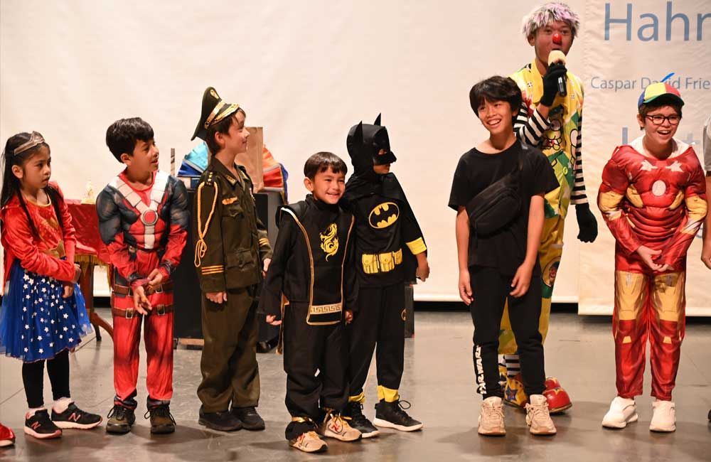 A group of children dressed in costumes are standing next to each other on a stage.