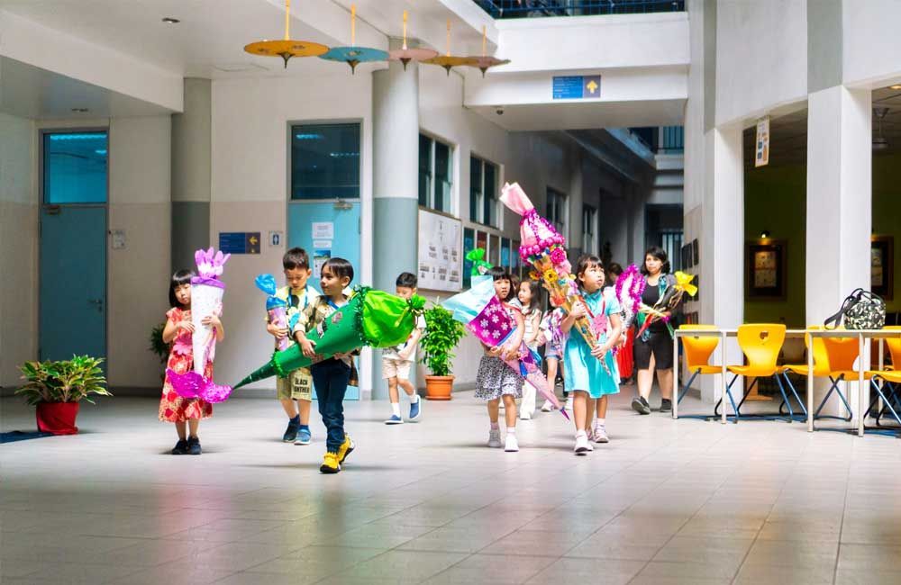 A group of children are walking down a hallway in a school.