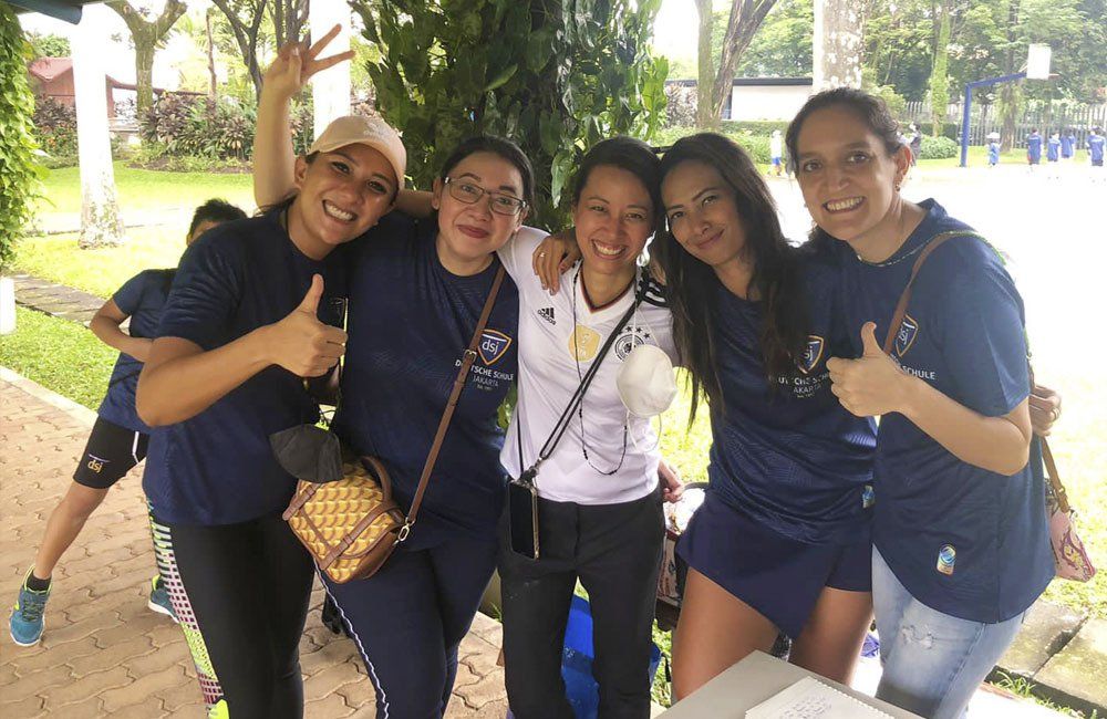 A group of young women are posing for a picture and giving a thumbs up.