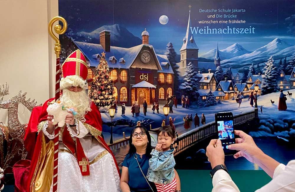 A man is taking a picture of a man dressed as santa claus.