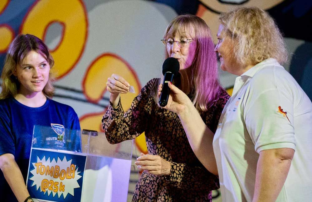 A woman is holding a microphone while standing next to two other women.