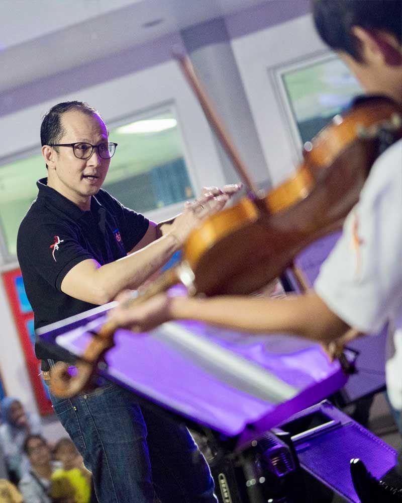 A man in a black shirt is playing a violin