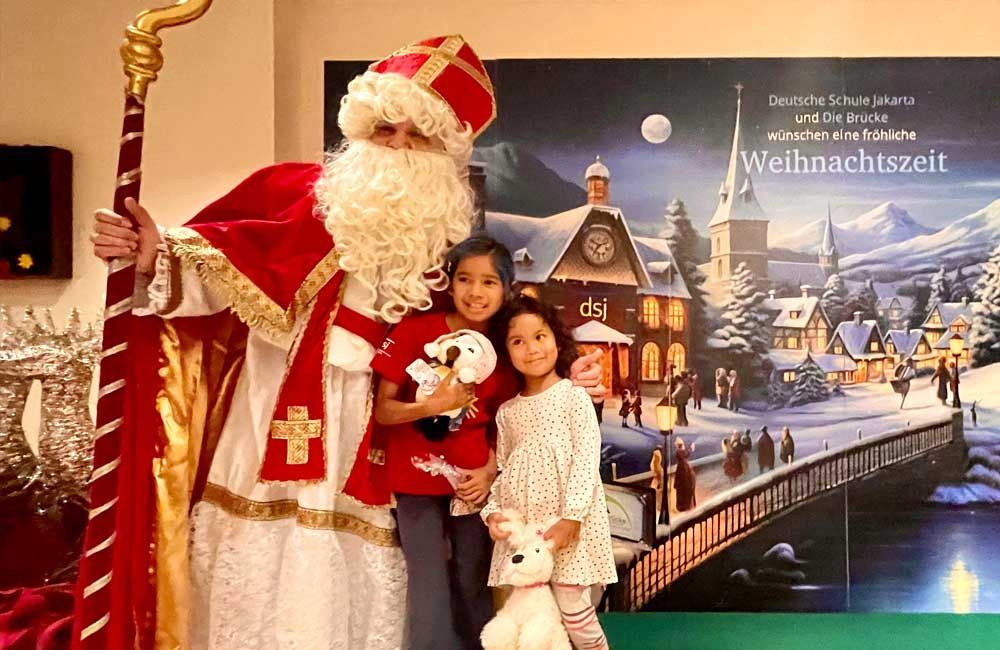 A man dressed as santa claus is posing for a picture with two little girls.