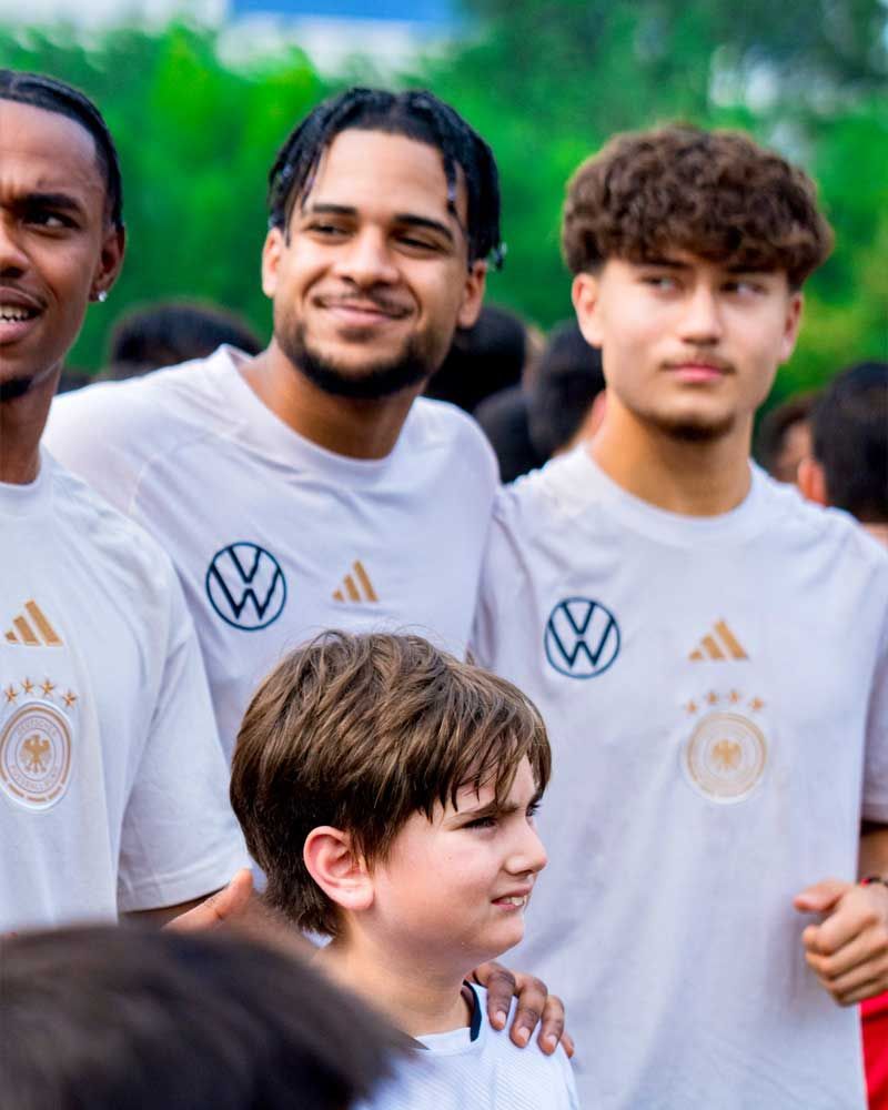 A group of young men wearing white adidas shirts are posing for a picture.