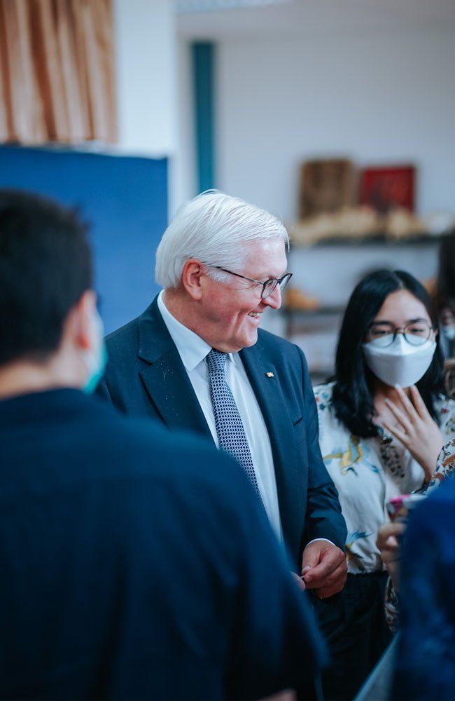 A man in a suit and tie is talking to a group of people.