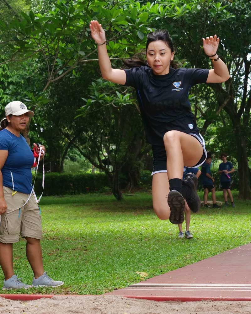A woman in a black shirt is jumping in the air