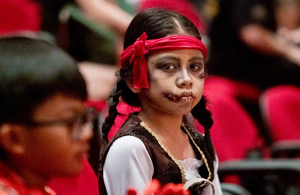 A little girl dressed as a pirate is sitting in a theater.