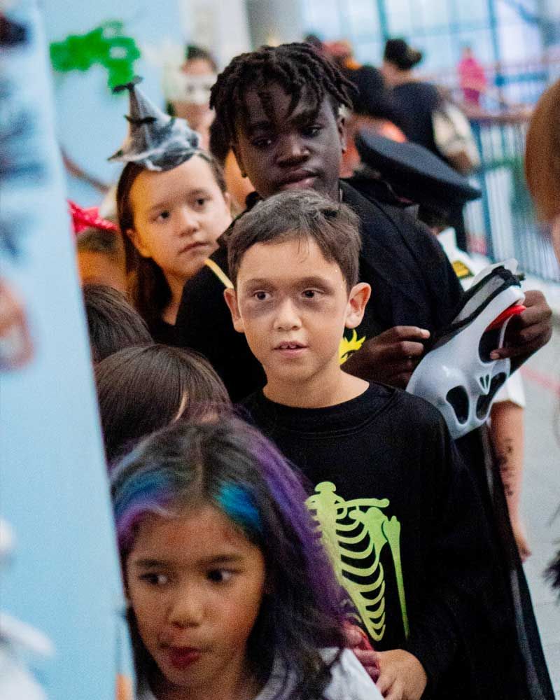 A group of children dressed in halloween costumes are standing in a line.