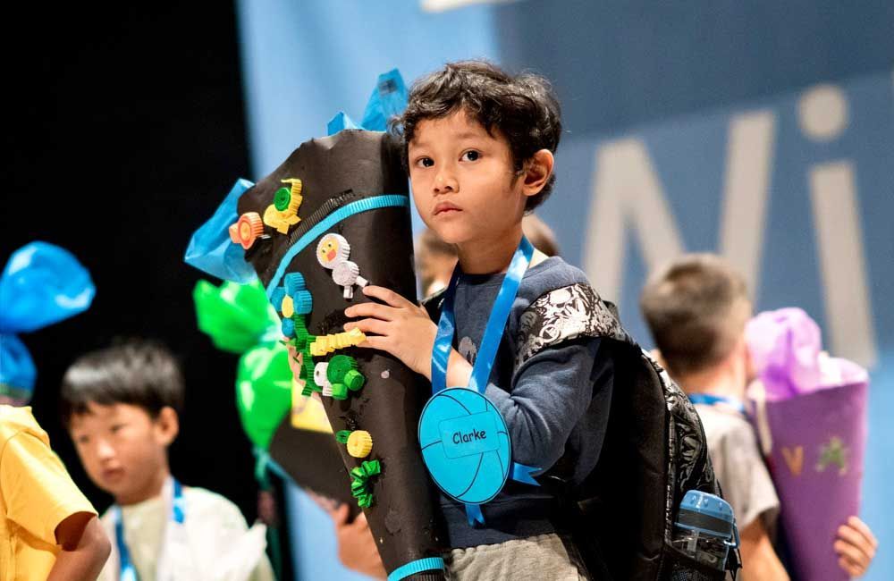 A young boy is holding a cone with a medal around his neck.