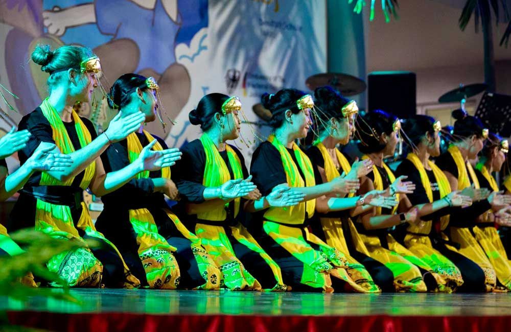 A group of women in yellow and black dresses are kneeling down on a stage.