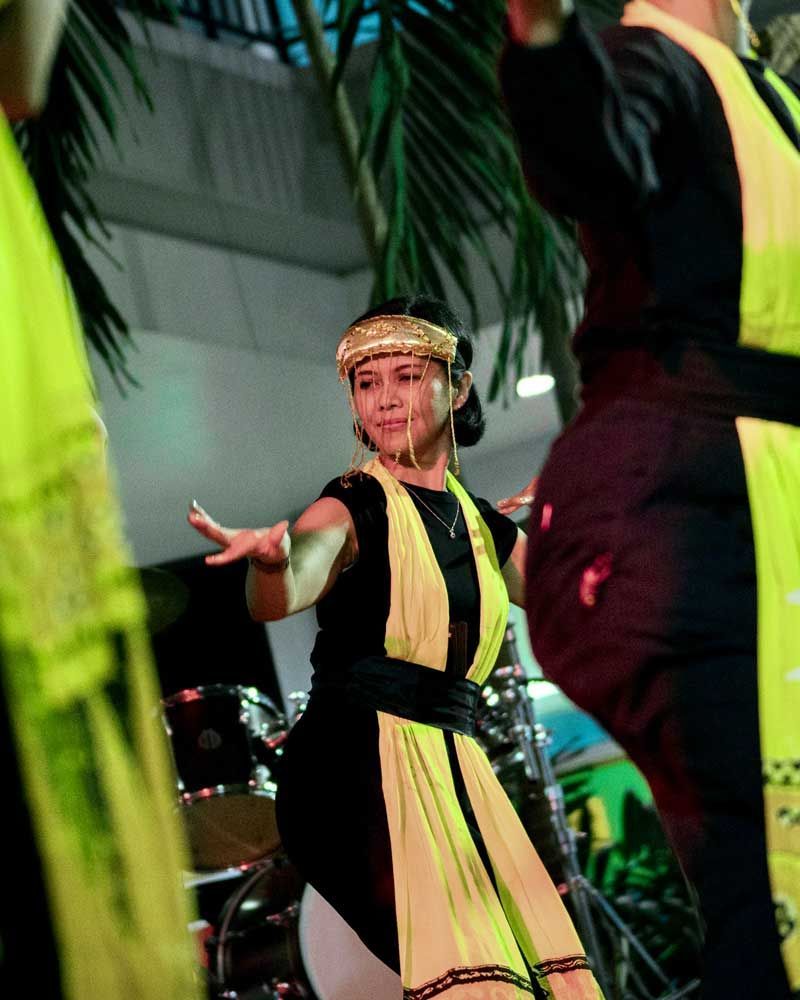A woman in a yellow and black dress is dancing in front of a drum set