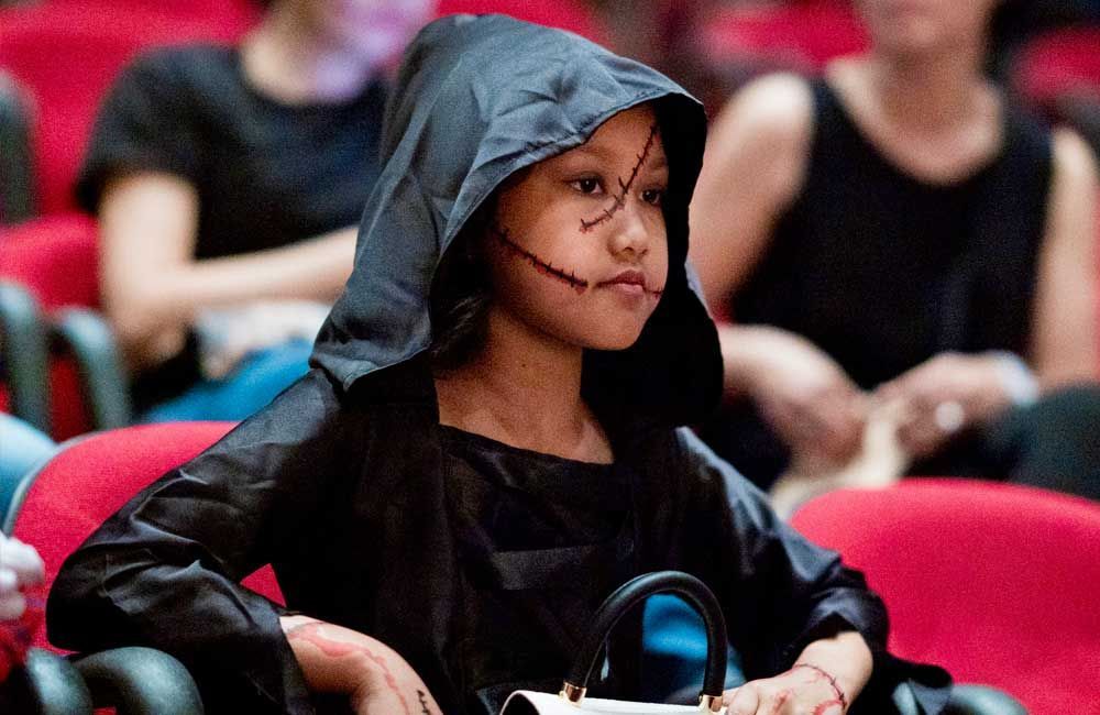 A child in a futuristic warrior costume holds a toy blaster, enjoying the Halloween