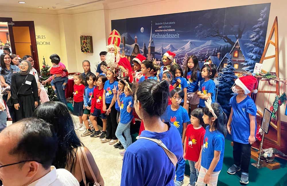 A group of children are standing in a room with santa claus.