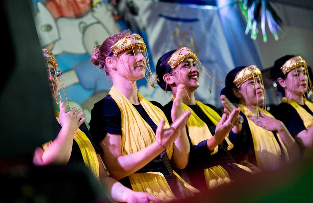 A group of women in yellow and black clothes are clapping their hands.