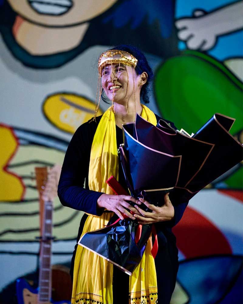 A woman is holding an umbrella in front of a cartoon character