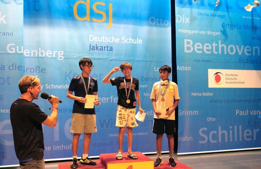 A man is speaking into a microphone in front of a wall that says beethoven