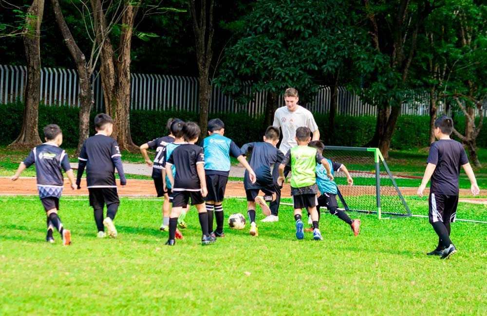 A group of young boys are playing soccer on a field with a coach.