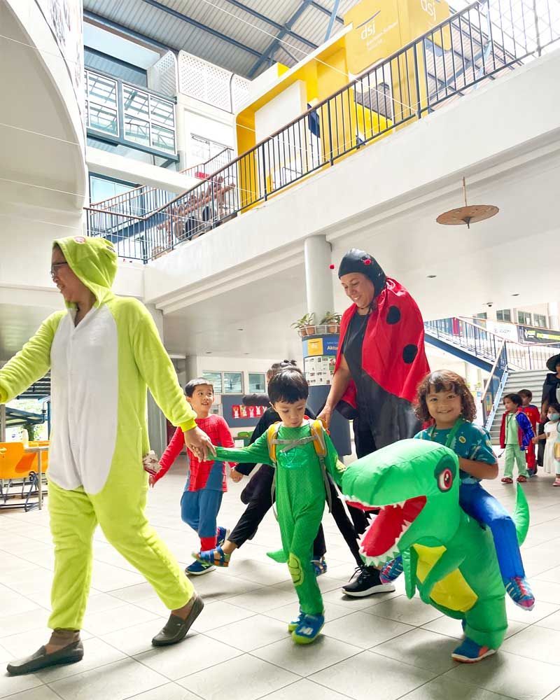 A group of children dressed in costumes are walking down a hallway.