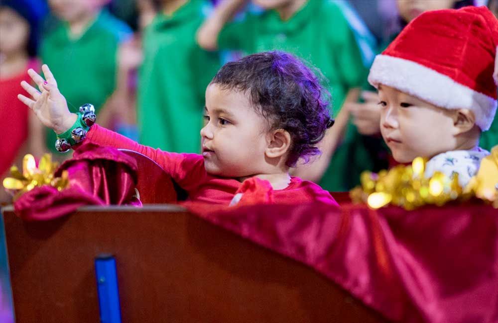 A group of children are sitting in a row wearing santa hats.