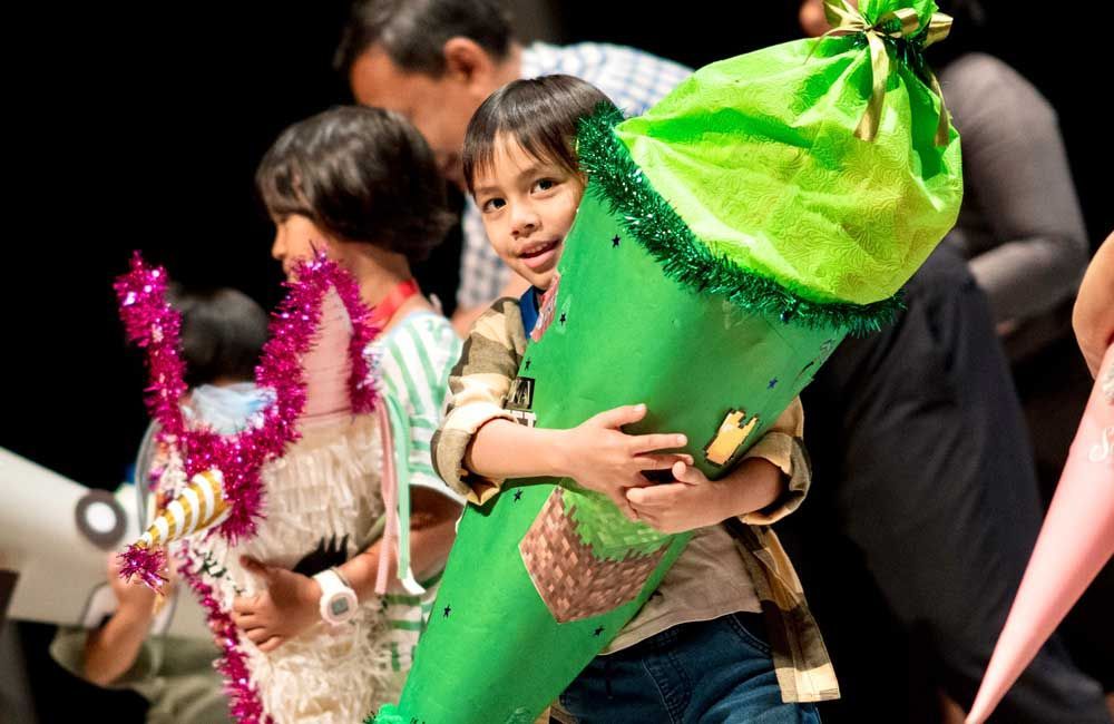 A young boy is holding a green cone in his hands.