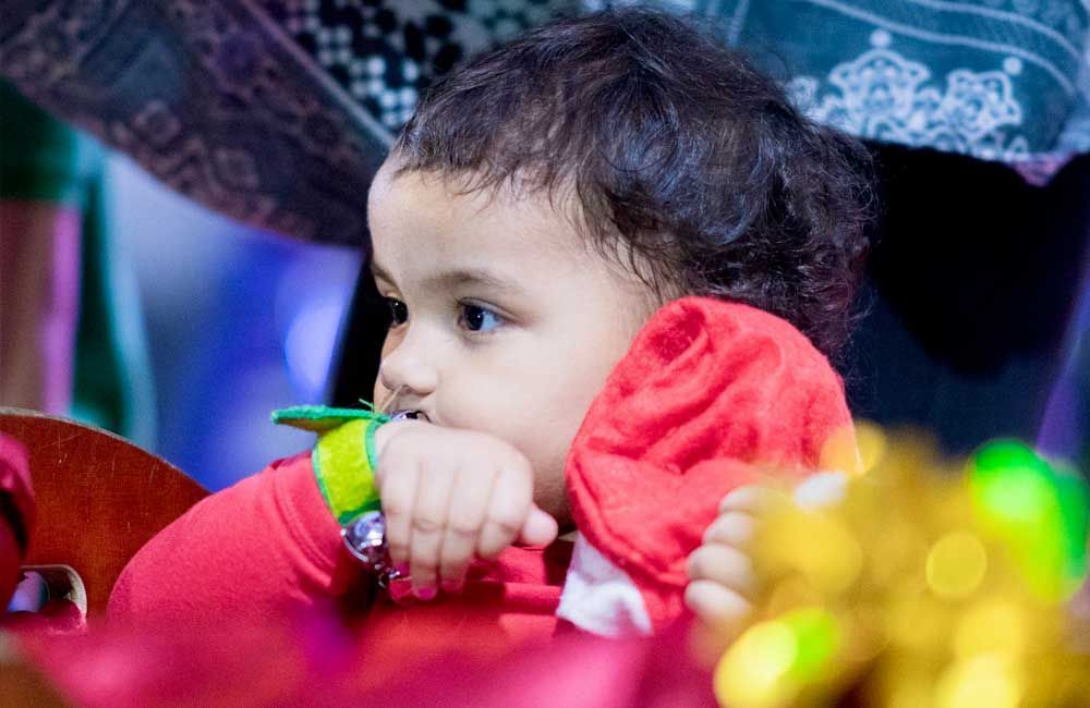A baby is sitting in a chair with a toy in his mouth.