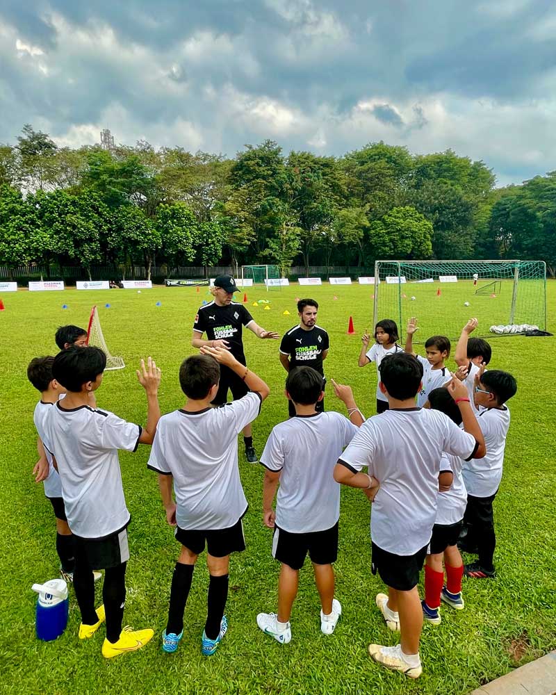 A group of young boys are standing in a circle on a soccer field.