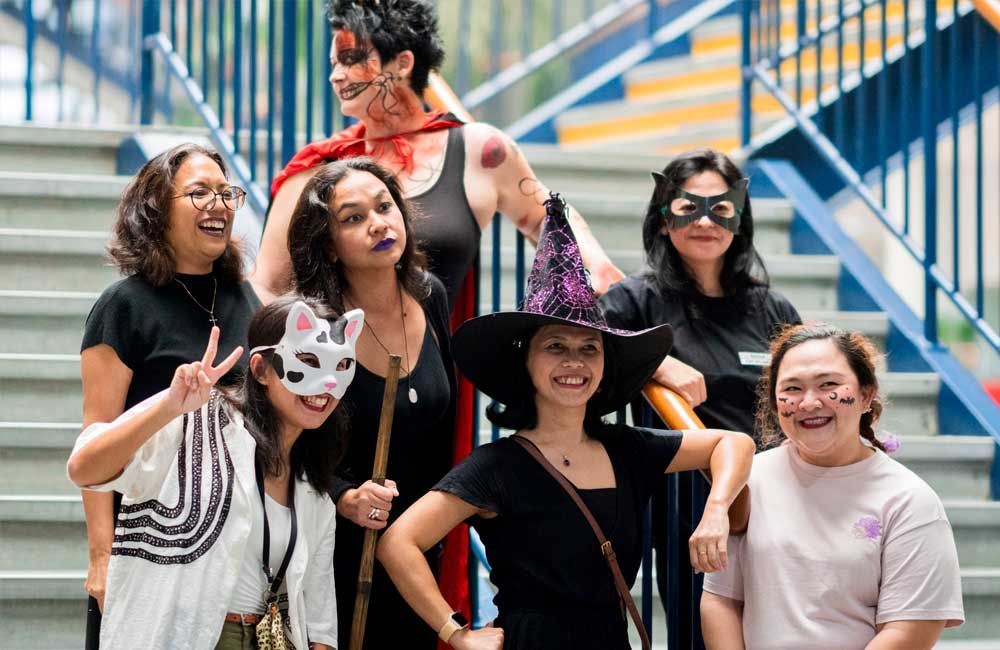 A group of women dressed in halloween costumes are posing for a picture.