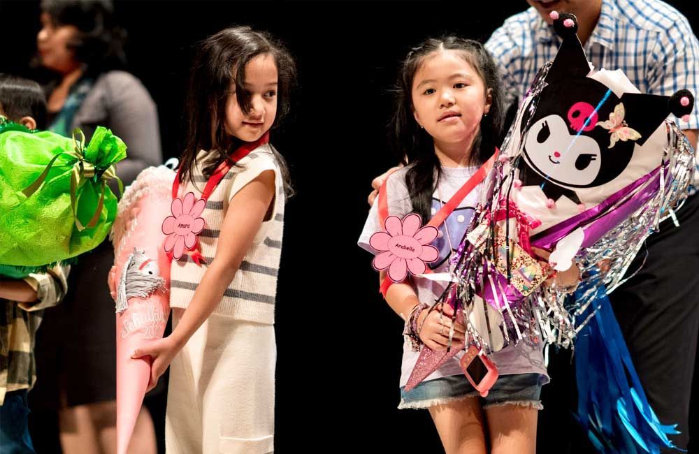 Two little girls are standing next to each other holding balloons.