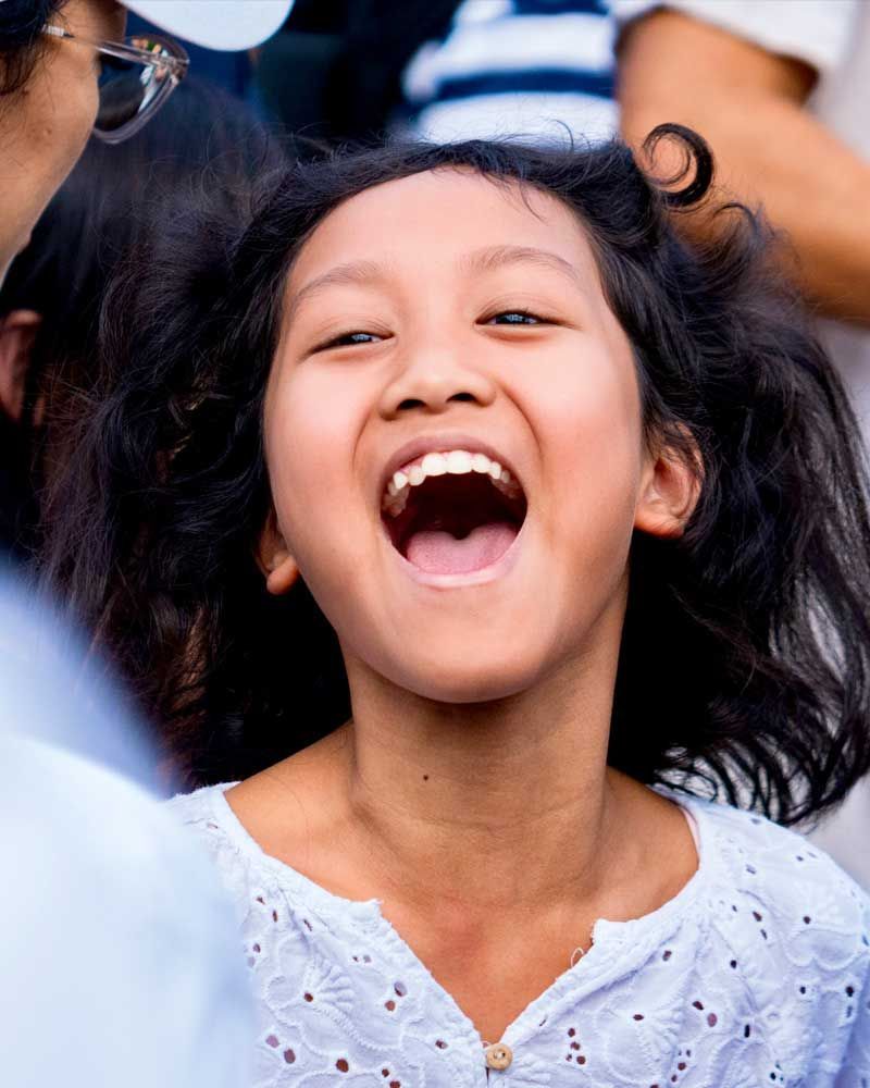 A young girl is laughing with her mouth open.