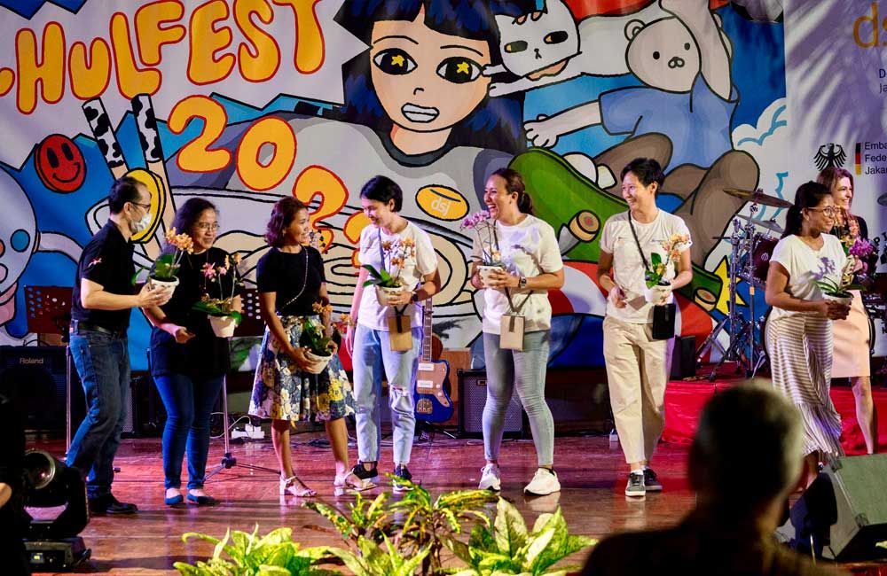A group of people are standing on a stage holding flowers.