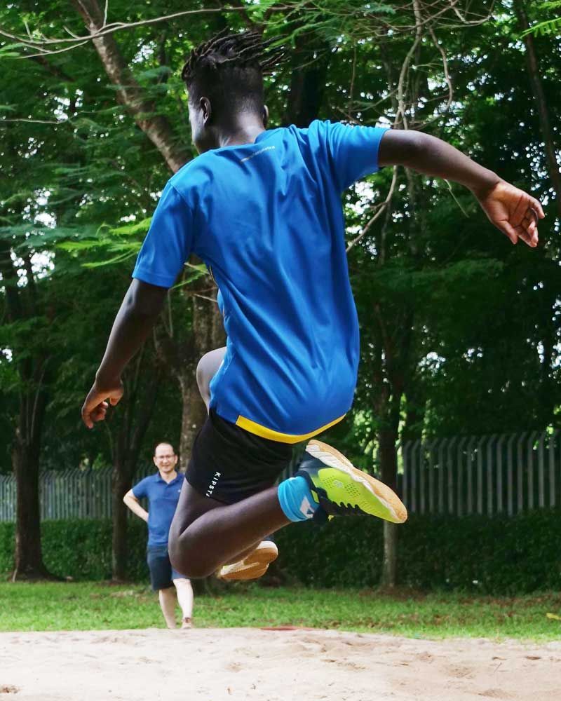 A man in a blue shirt is jumping in the air