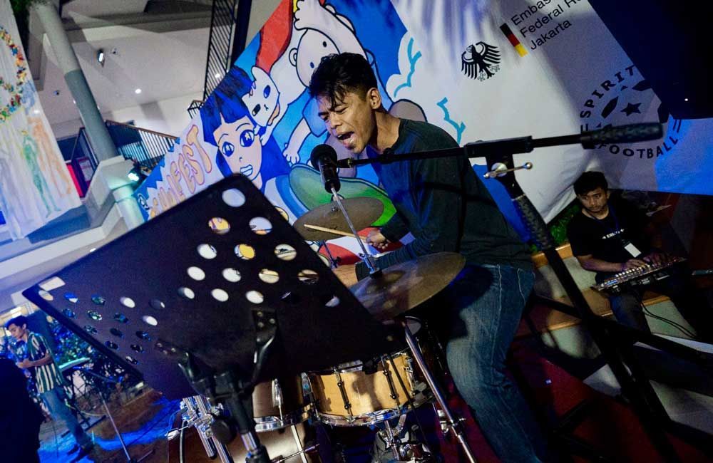 A man is playing drums and singing into a microphone.