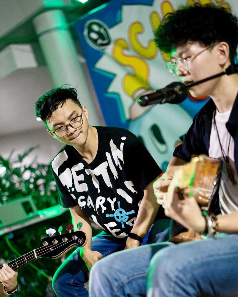 A man is singing into a microphone while another man plays a guitar.