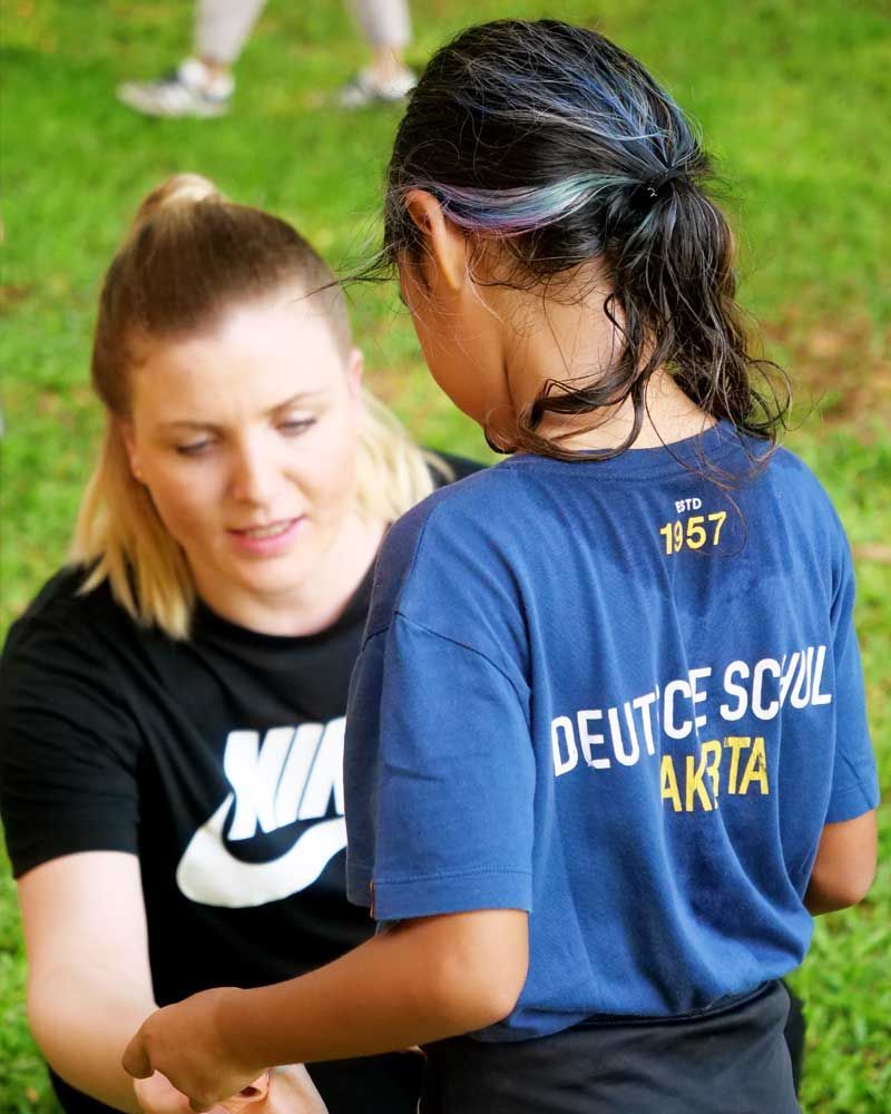 A girl wearing a blue shirt that says deuce school aksta