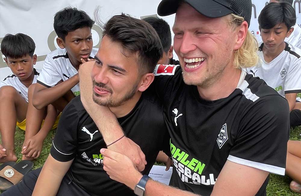 Two men are hugging each other in front of a group of children.