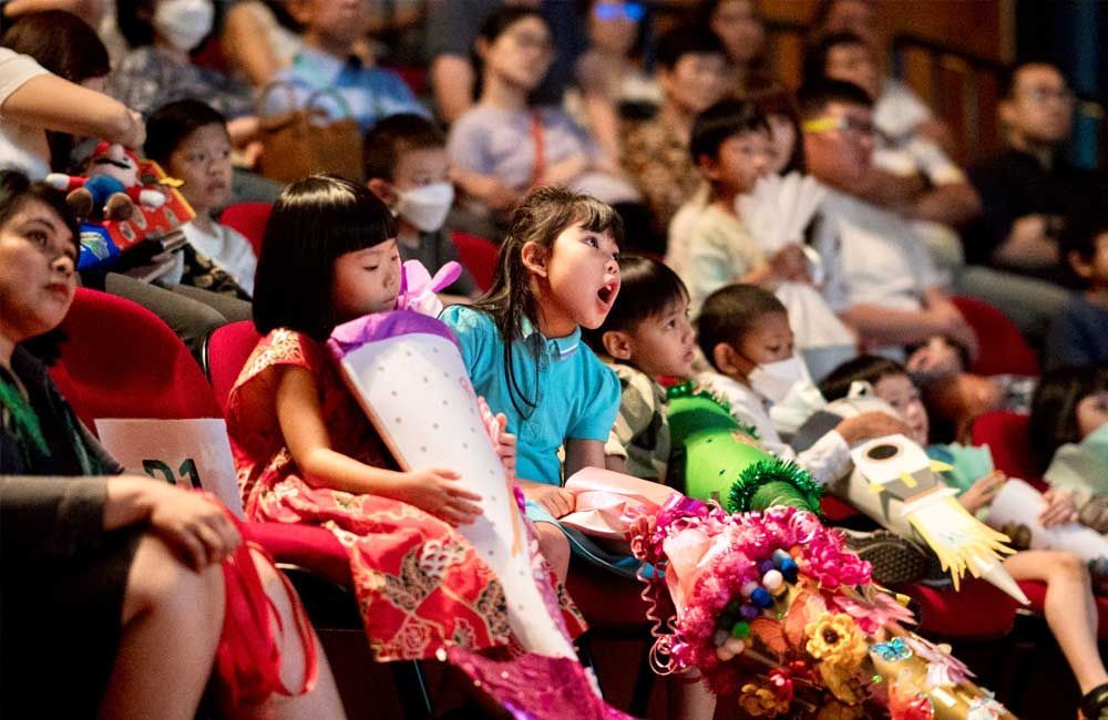 A group of children are sitting in a theater watching a show.